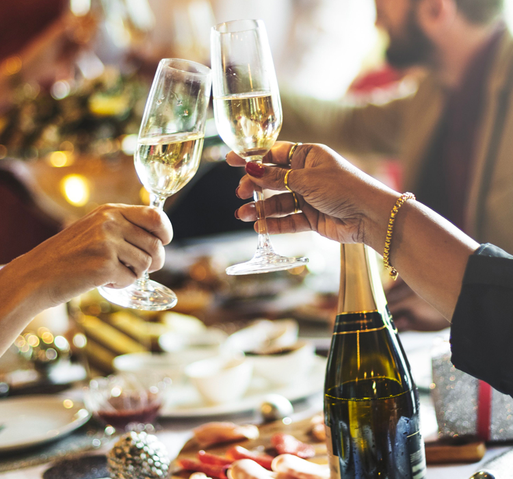 close up of two people toasting champage together over a fest of a meal