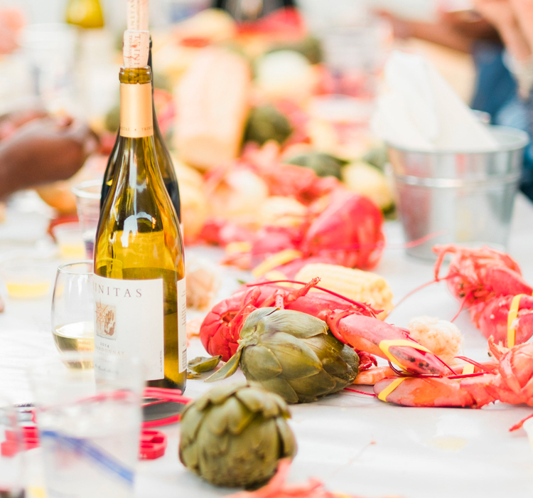 close up of a long table filled with fresh lobsters and wine for customer to enjoy during a lobster fest