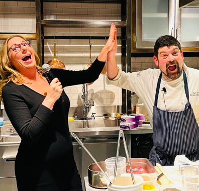 fun and lively host giving a chef a high-five during a cooking demonstration