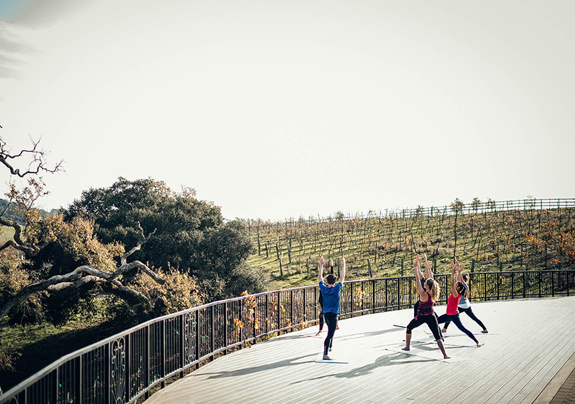 an outdoor yoga class being taught on a patio at Meritage Resort facing the vineyards