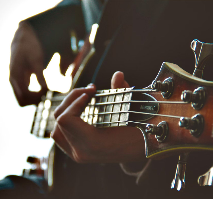close up of a bass player stringing the guitar