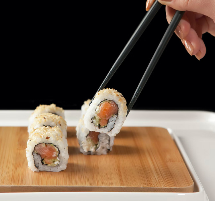 chopsticks picking up fresh sushi roll