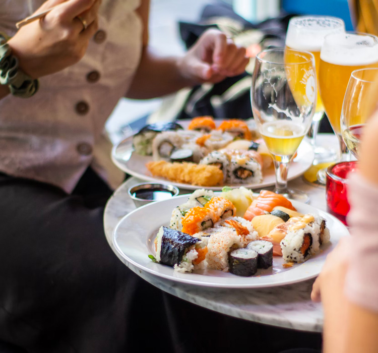 view of a table of guests enjoying a sampling of sushi and beer