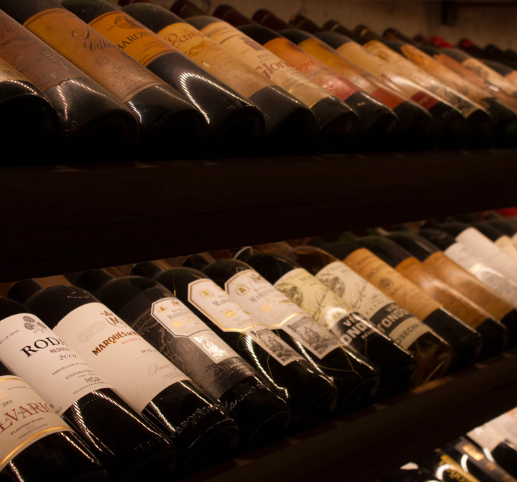close up of two tiers of wine bottles from various vineyards resting on shelfs