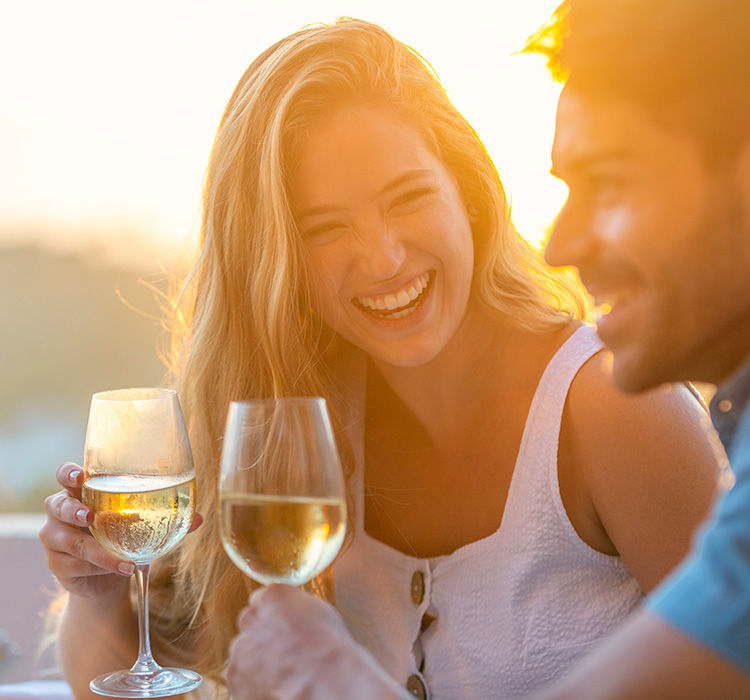 a couple sitting outside enjoying a glass of wine at sunset