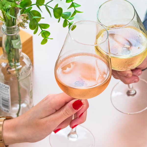 close up of a man and woman toasting wine glasses filled with a rose and a white wine