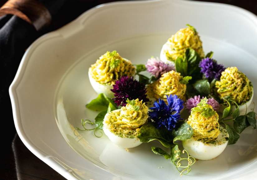 deviled eggs on a plate with flower garnishes