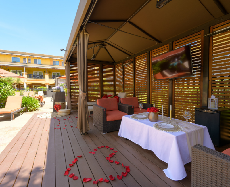 View of a pool cabana with a set up table and a rose petals shaped hard next to it