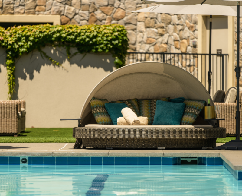 View of a circular day bed by the pool with two rolled towels on top