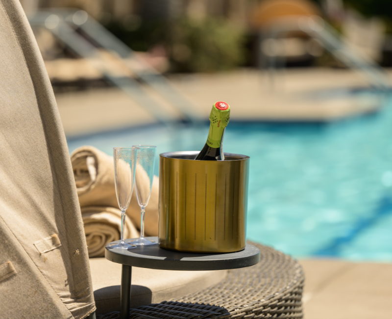 close up of a daybed with a table next to it with a champagne bottle and two glasses