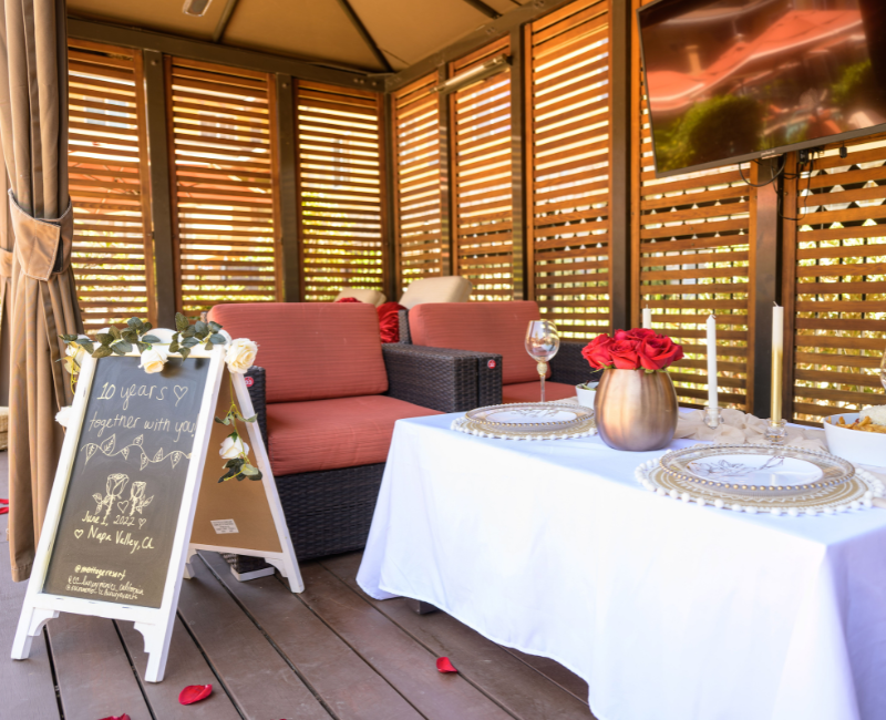 Pool cabana with a set up table, two red chairs, tv and a handwritten sign