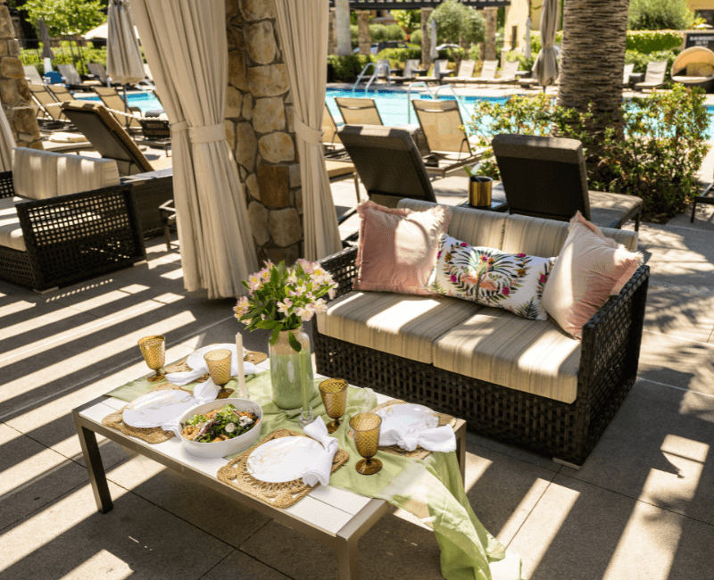 shaded cabana by the pool with a sofa and a set up table with flowers