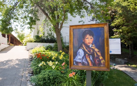 an exhibition painting of a little boy placed in the middle of a garden 