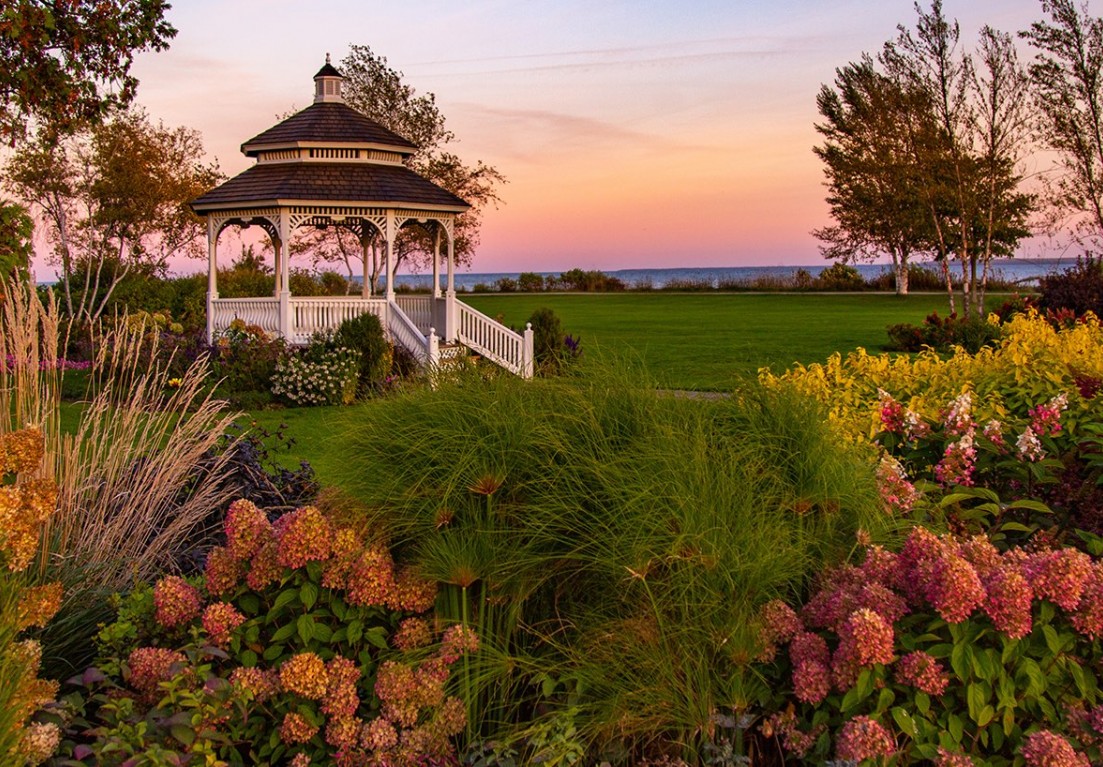a garden with a kiosk in the middle surrounded by flowers