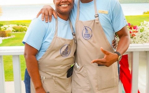 a man and a women smiling and wearing aprons