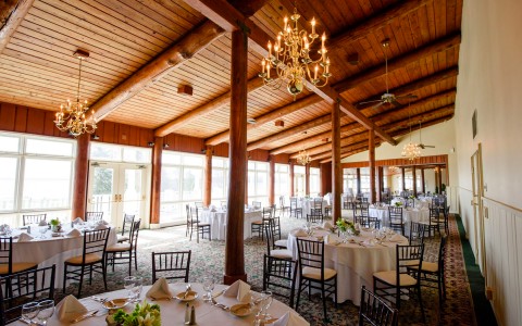 event venue with a slanted wooden ceiling and round tables with wedding table settings