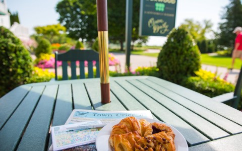image of a table outside with a newspaper and croissants on the table 