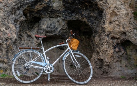 blue bicycle parked next to a wall of stone 