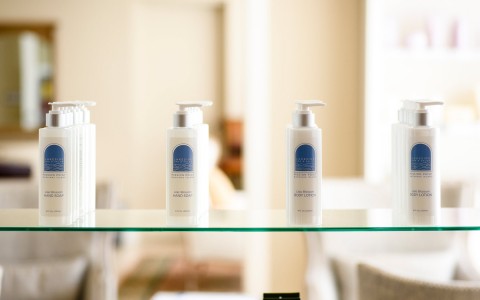 close up of lotion bottles sitting on a glass shelf 