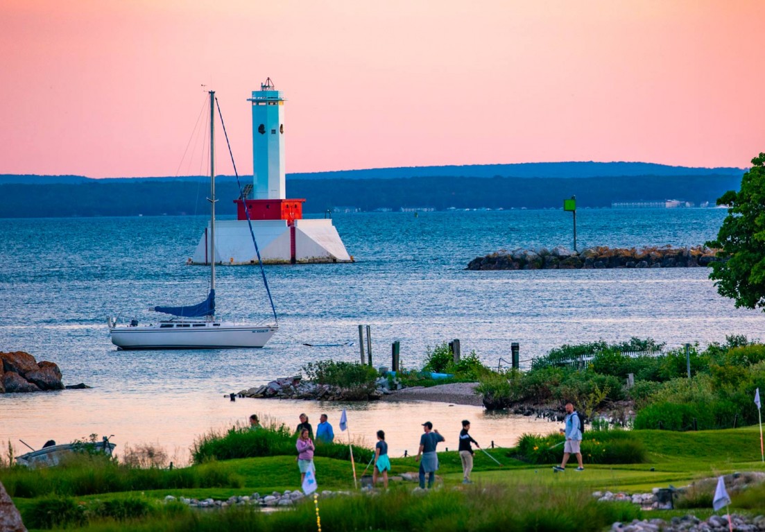 aerial image with a view of a lighthouse and a sailboat in the water