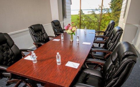 In door meeting area with wood table and 6 black leather chairs