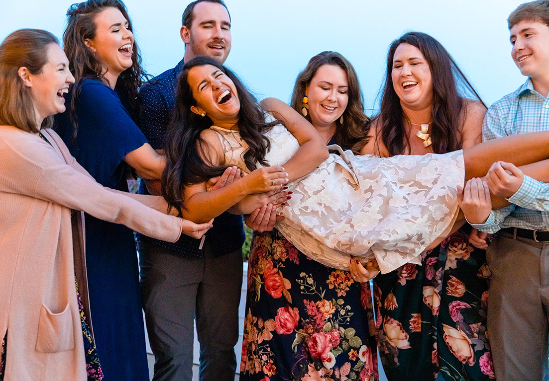 people holding a woman in their arms while smiling and laughing