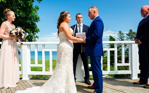 bride and groom holding hands at the front of their wedding with the officiant and maid of honor and best man behind them