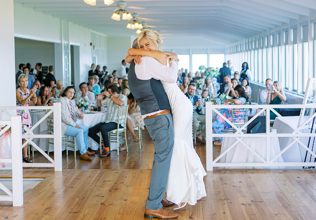 bride and groom hugging at a wedding reception with people in the background