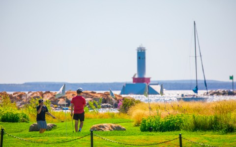 golf course with the lighthouse and a boat behind it in the lake 