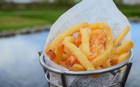 close up of french fries in a metal tin outside 