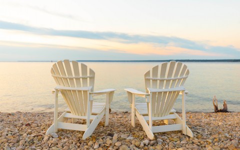 two white lawn chairs facing the lake