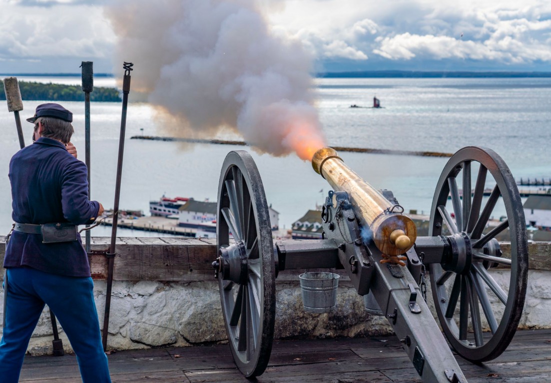 a man next to a canon firing into the water