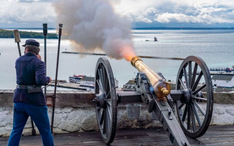 a man next to a canon firing into the water
