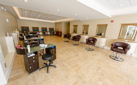 inside a salon with dark brown chairs and a pedicure area in the back