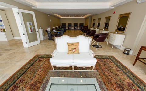 salon from the front with a big white chair and the salon chairs in the back 