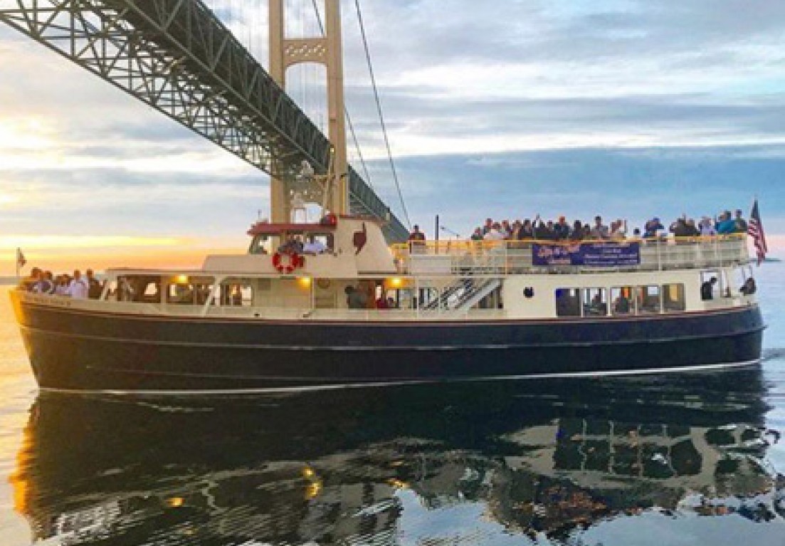 a boat sailing on the sea and crossing under a bridge