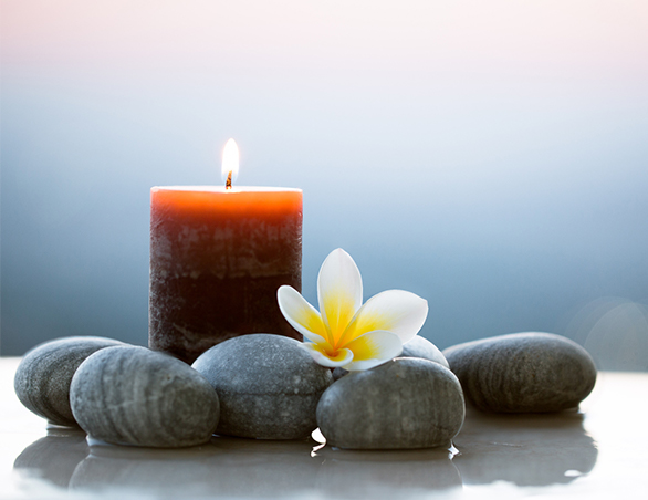 candle with rocks and flower