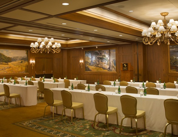 meeting room with two chandeliers and white rectangular tables with gold chairs