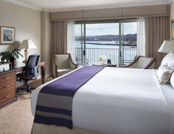 harbor view room with king bed and large picture window and balcony