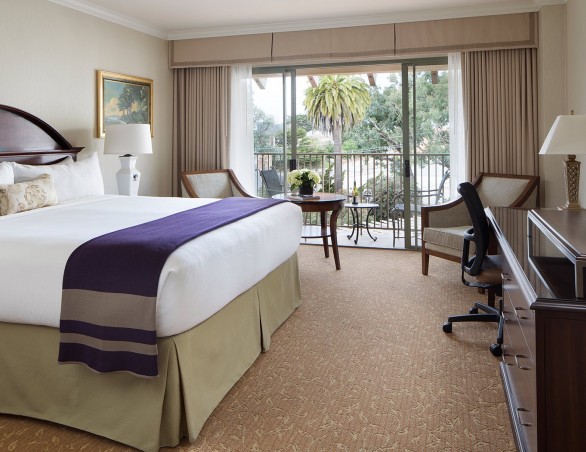 inland view room with king bed with white linens and a purple blanket