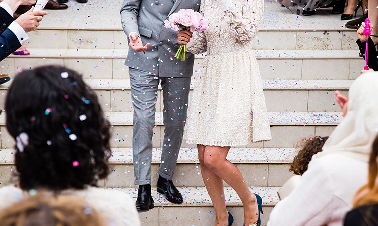 bride and groom coming down steps with confetti being thrown
