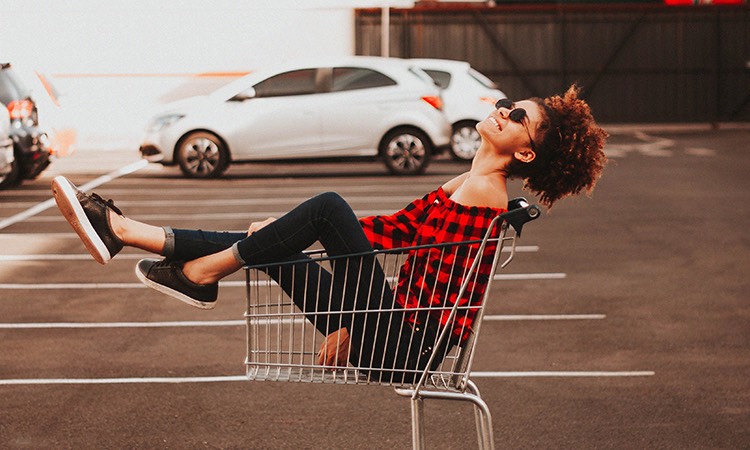 Trendy woman sitting in a shopping cart