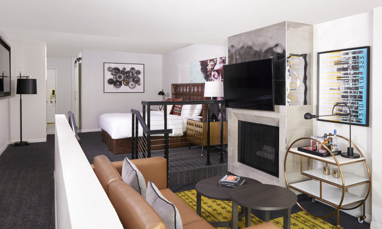 ADA room with brown leather couch fireplace with large tv seating and bedroom area
