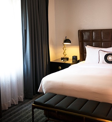 Guest room bed with white linens and leather headboard