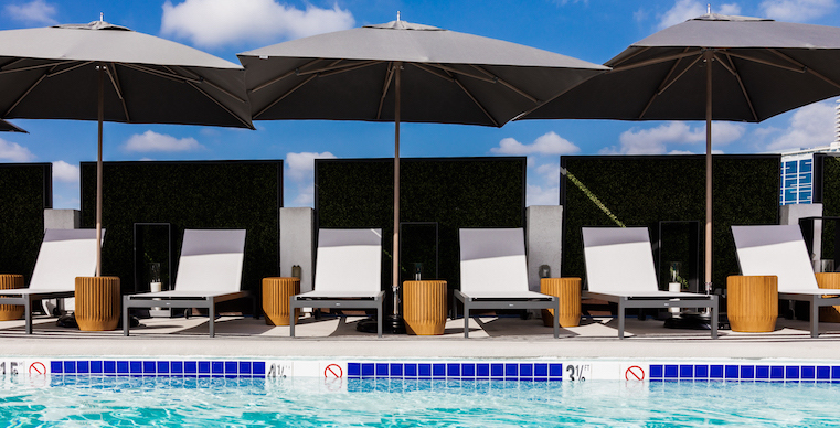 rooftop pool with white loungechairs and grey umbrellas for shade