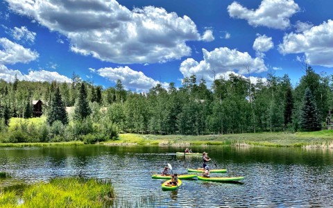 a group of people kayaking in a small lake surrounded by lots of green trees