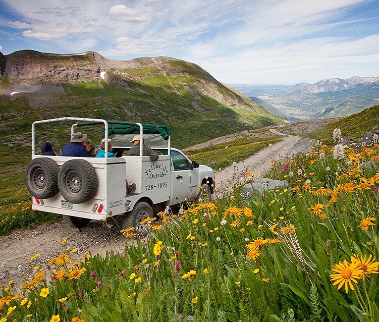 a white truck with people sitting in the back and looking at the landscape around them