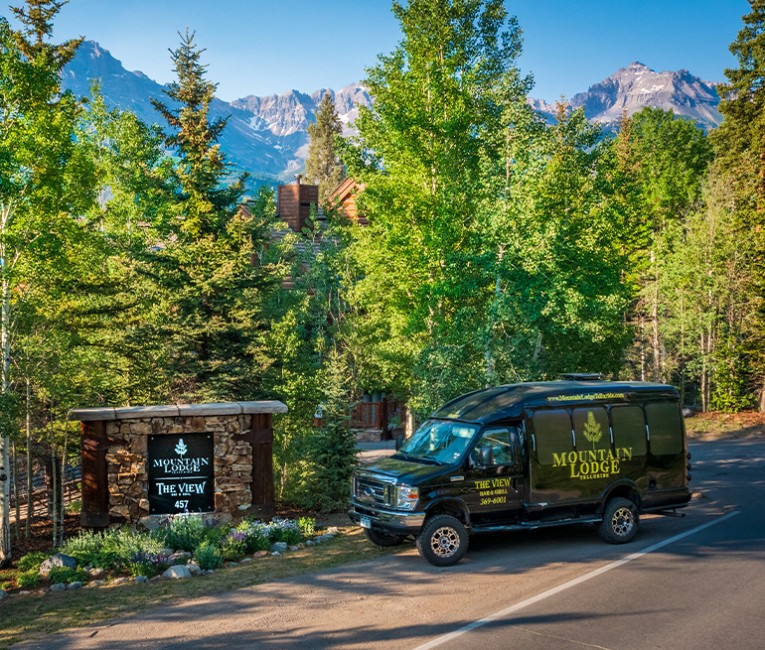 a black and yellow mountain lodge van parked at the entrance to the property