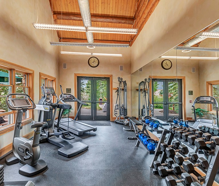 a fitness room with weights and machines for cardio