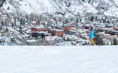 a person skiing down the mountain with the city in the distance